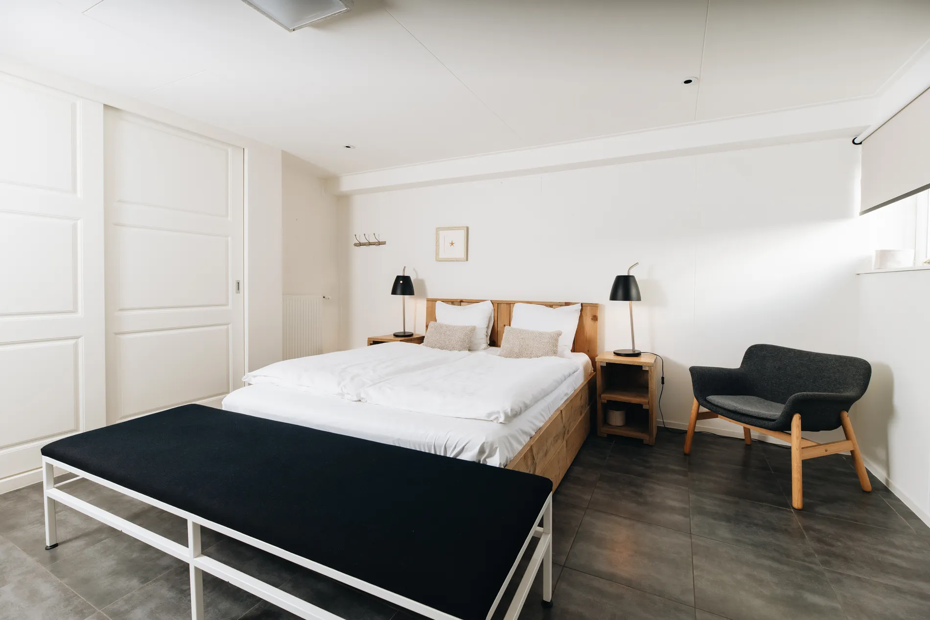 Ruime master bedroom met een groot tweepersoonsbed en strakke witte kastenwand.